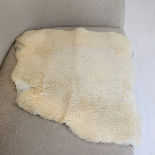 Soft, natural medical sheepskin pad placed on a chair for comfort and pressure relief.