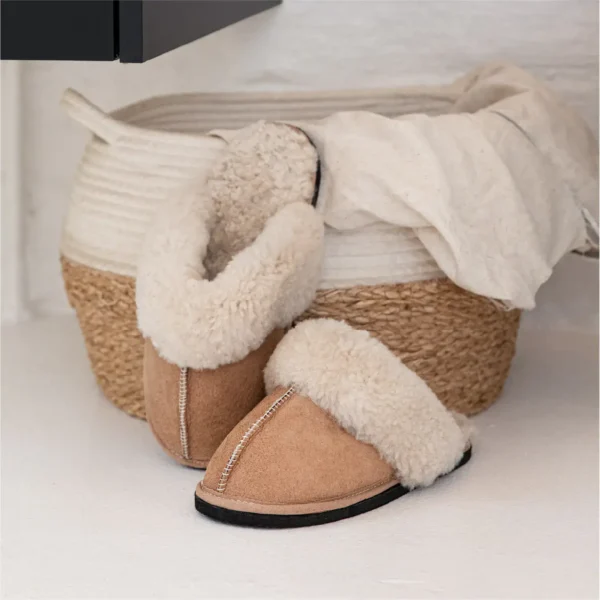Namaqua Classic sheepskin slippers resting next to a woven basket with a blanket.